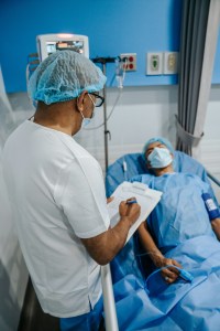 a man in scrubs communicating with a patient, explaining his diagnosis.